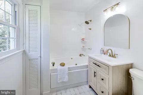 a bathroom with a bathtub sink and mirror