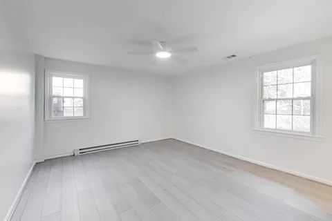 an empty room with wooden floor and windows