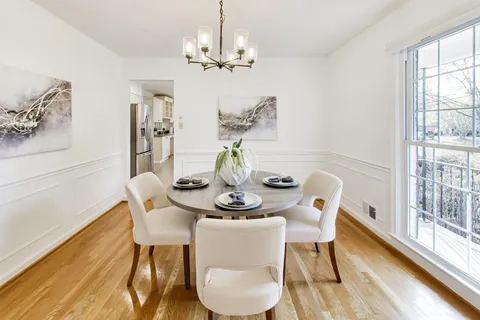 a dining room with furniture a large window and wooden floor