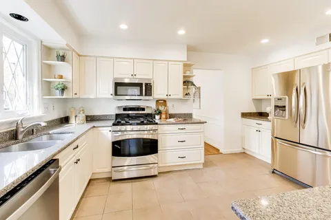 a kitchen with kitchen island white cabinets stainless steel appliances and window