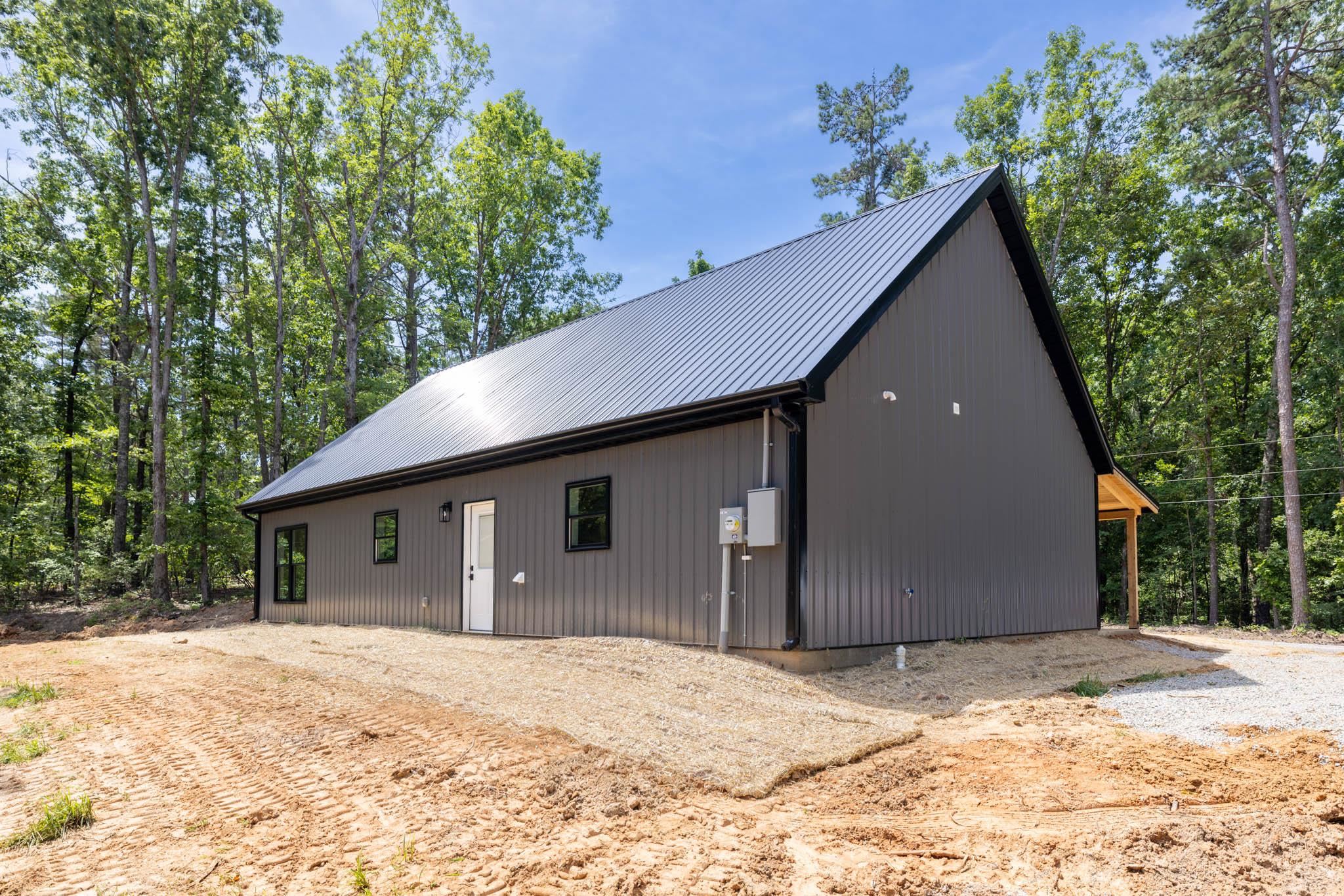 37 William Teague Lane Ramer, TN 38367 - Photo 8 of 39 Modern barn-style structure featuring dark gray vertical siding, a black metal roof, and black-framed windows