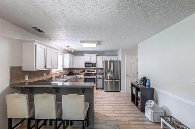 a kitchen with a dining table chairs and refrigerator