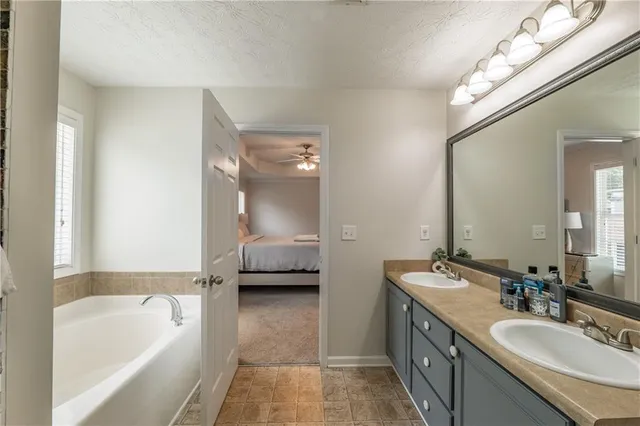 a en suite bathroom with a granite countertop tub double vanity sink and a mirror
