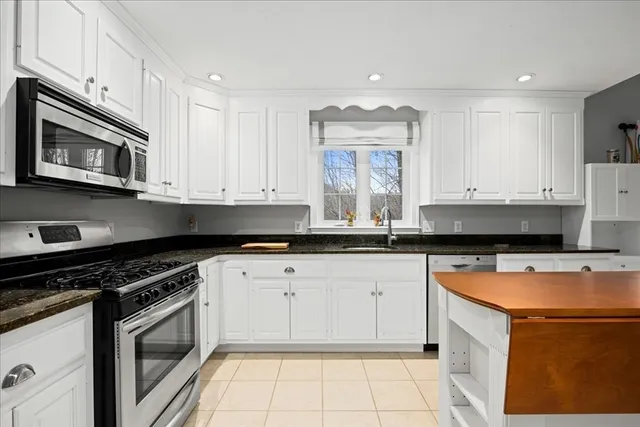 a kitchen with stainless steel appliances granite countertop a stove a microwave and a white cabinets