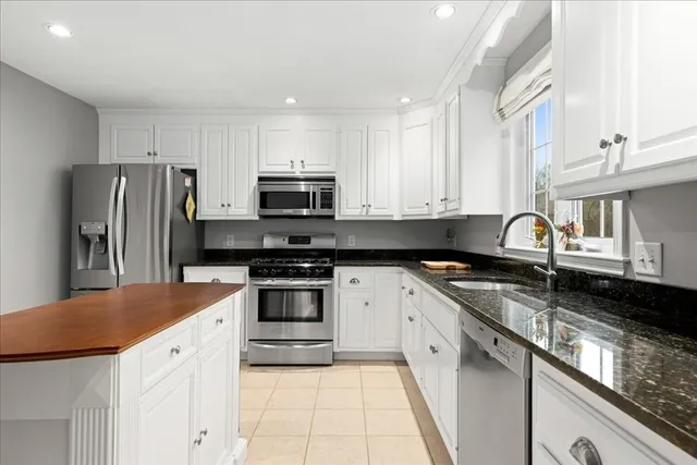 a kitchen with stainless steel appliances granite countertop a sink stove refrigerator and cabinets
