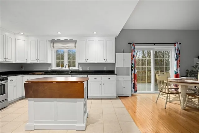 a kitchen with granite countertop a stove a sink a dining table and chairs