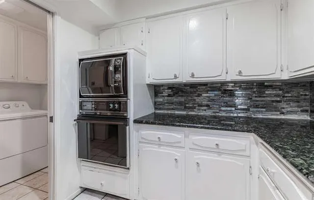 a kitchen with granite countertop white cabinets and stainless steel appliances