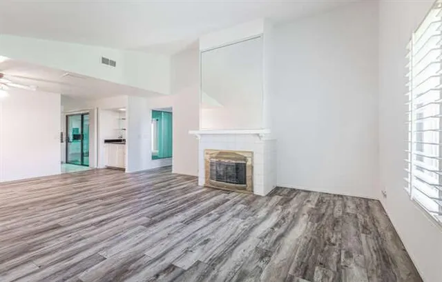 wooden floor fireplace and windows in an empty room