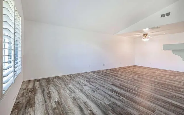 a view of empty room with wooden floor and fan
