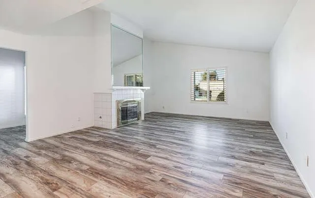 a view of empty room with wooden floor and fireplace