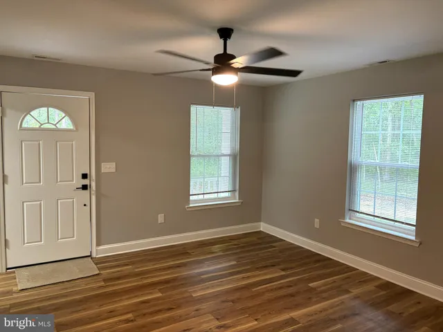 a view of an empty room with a window and wooden floor