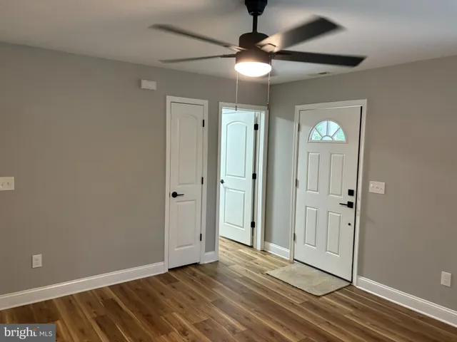 an empty room with wooden floor fan and windows