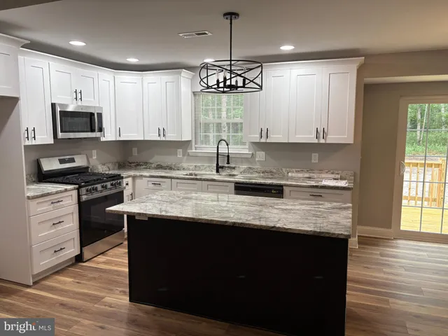 a kitchen with stainless steel appliances granite countertop a sink a stove and cabinets