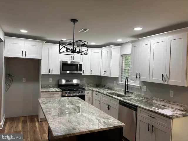 a kitchen with kitchen island granite countertop a stove a sink a refrigerator and a microwave