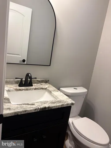 a bathroom with a granite countertop sink and a toilet