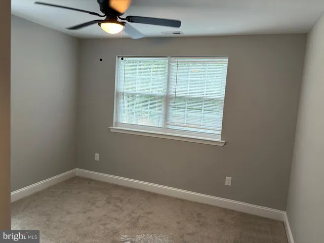 an empty room with a window and a fan