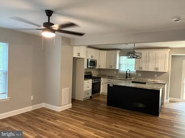 a kitchen with stainless steel appliances granite countertop a sink cabinets and wooden floor