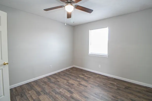 an empty room with a window and a ceiling fan