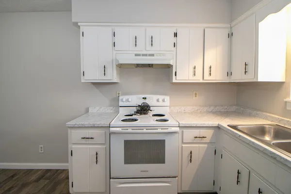 a kitchen with granite countertop white cabinets and white stove