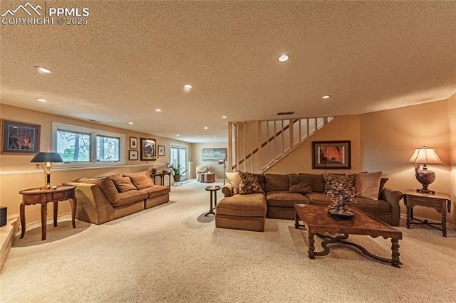 7175 Higher Ridges Court Colorado Springs, CO 80919 - Photo 30 of 50 Carpeted living room with visible vents, recessed lighting, stairway, and a textured ceiling