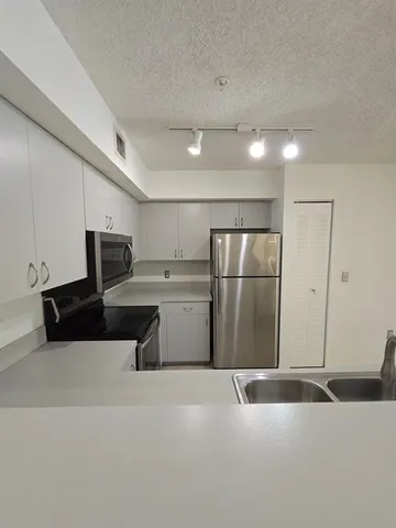 a large kitchen with granite countertop a sink and white cabinets