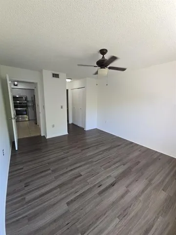 a view of a room with wooden floor and a ceiling fan
