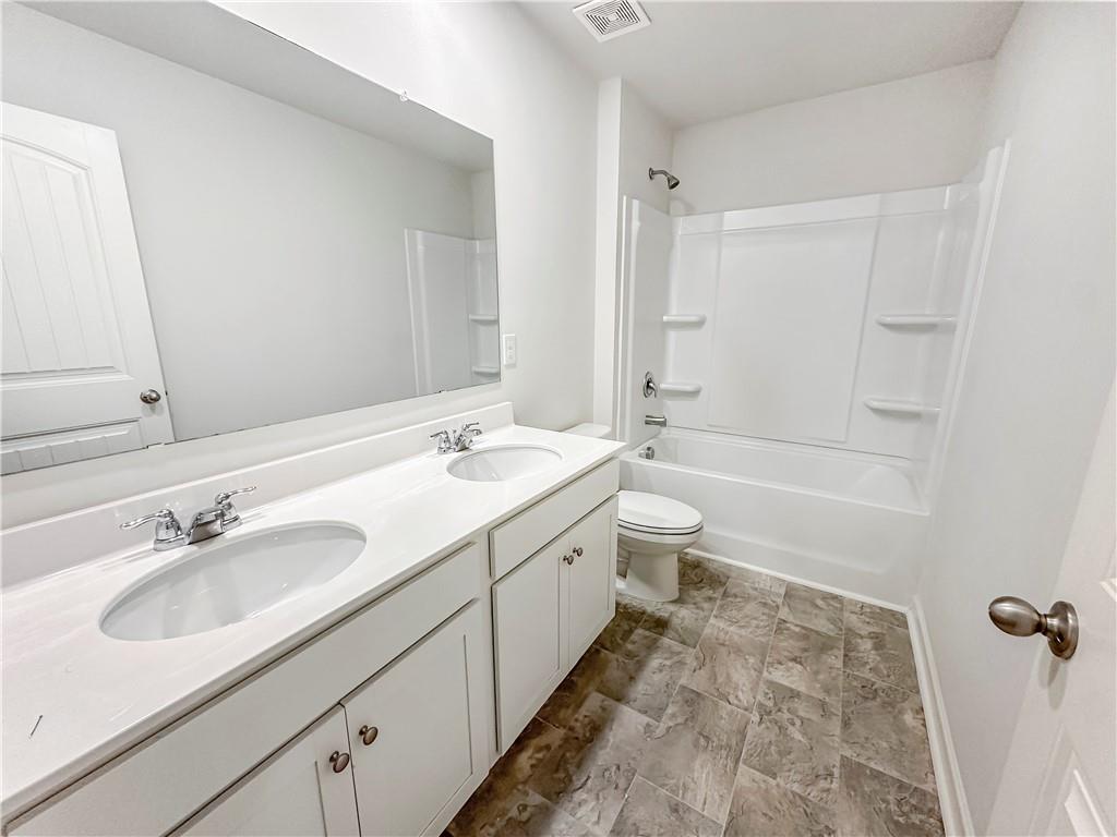 965 Athena Bend Fairburn, GA 30213 - Photo 16 of 37 a bathroom with a double vanity sink toilet a large mirror and shower