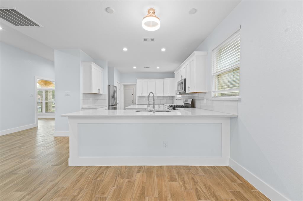 3807 Winding Road Arlington, TX 76016 - Photo 9 of 23 Bright kitchen featuring white cabinetry, light countertops, stainless steel appliances, and wood-finish flooring