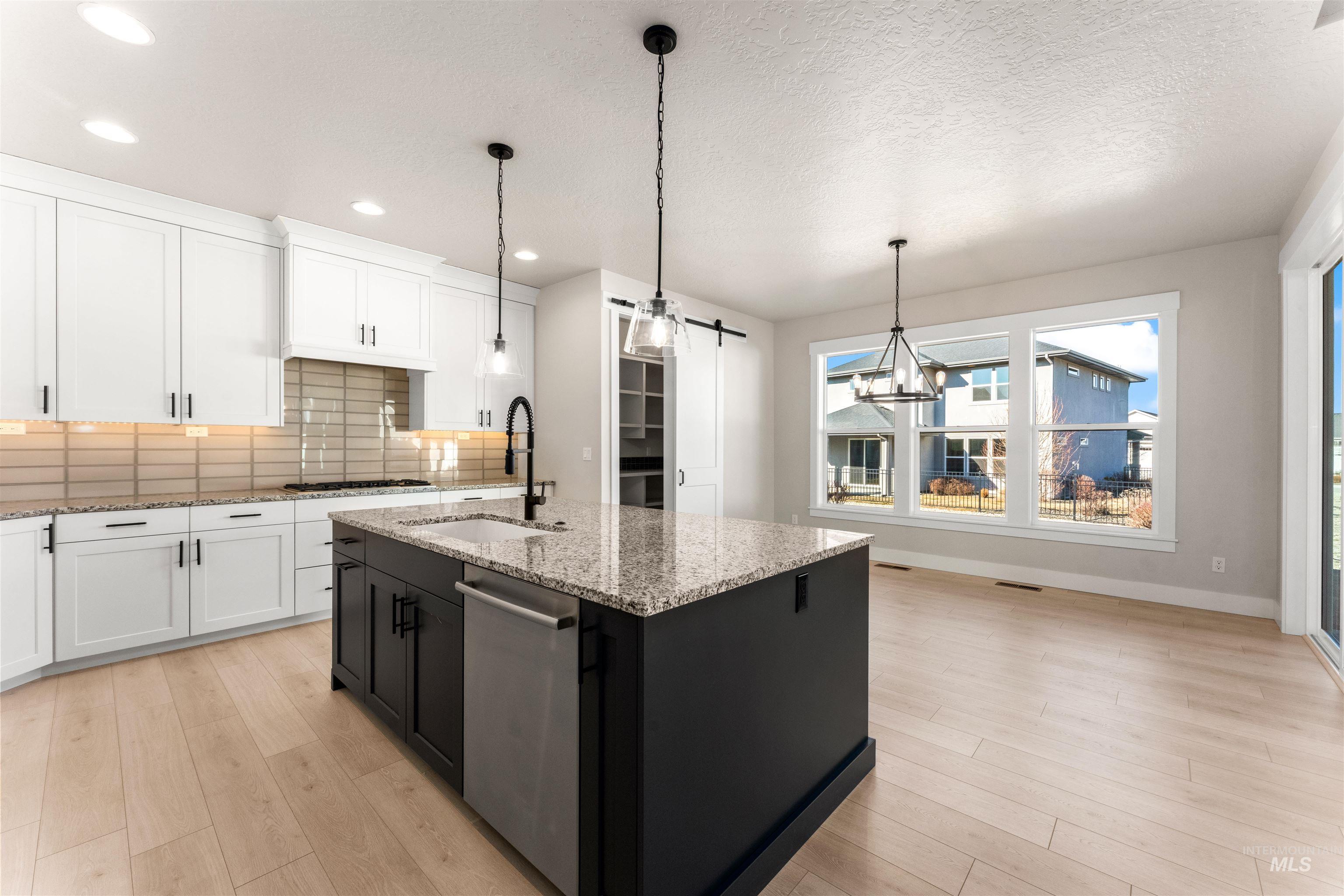 8084 Tandy Cv Street Middleton, ID 83644 - Photo 12 of 46 Kitchen featuring dual tone cabinets, tasteful backsplash, light wood-type flooring, light stone countertops, and dishwasher