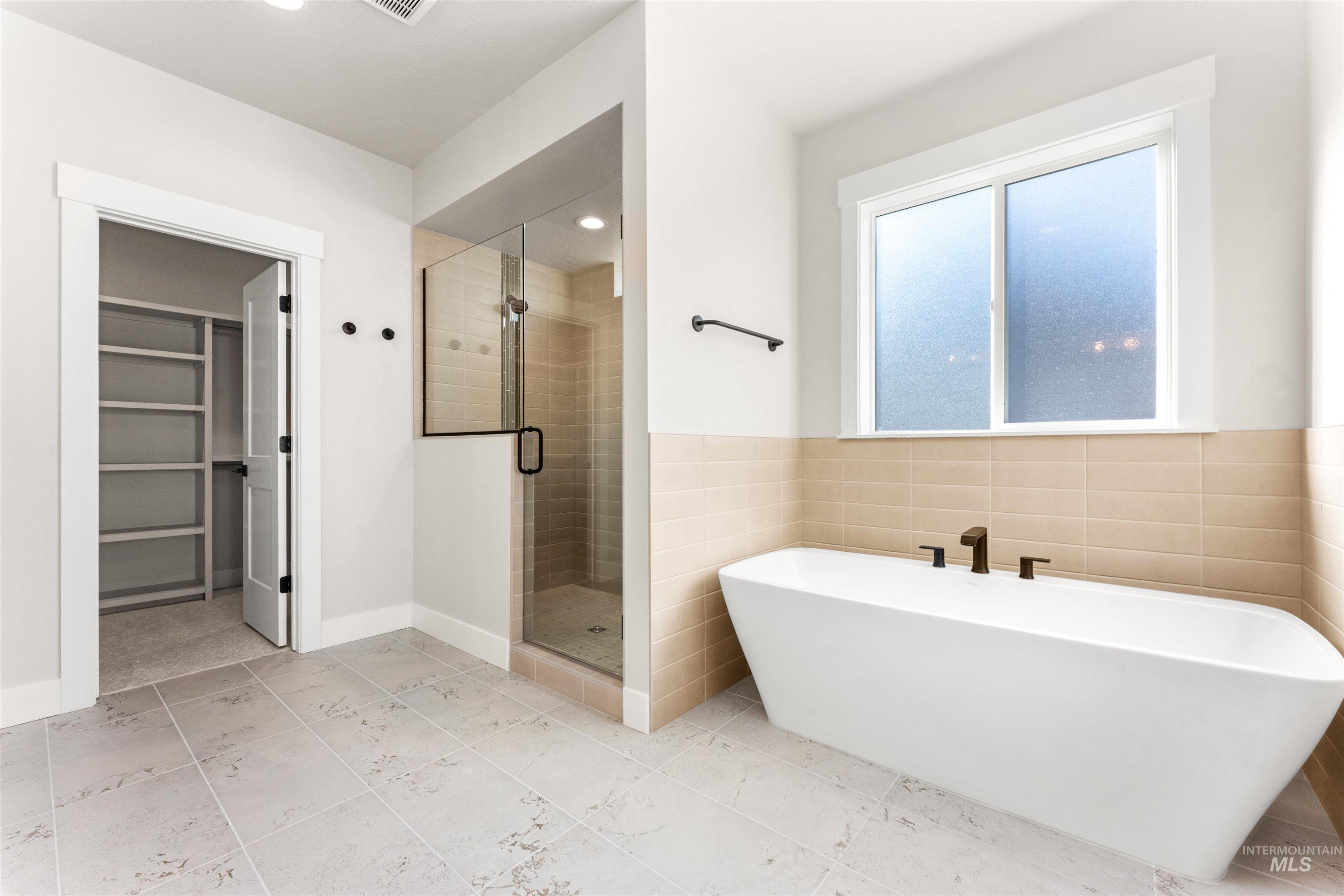 8084 Tandy Cv Street Middleton, ID 83644 - Photo 20 of 46 Full bathroom with a shower stall, tile walls, a freestanding tub, a spacious closet, and wainscoting