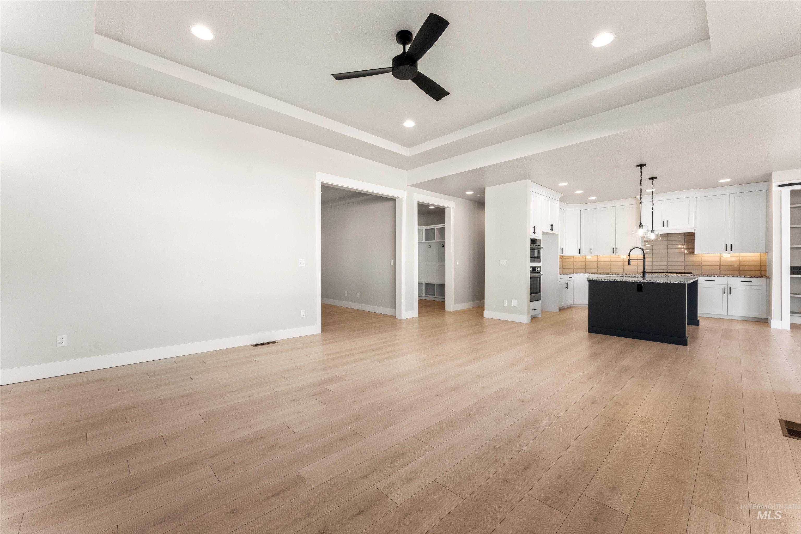 8084 Tandy Cv Street Middleton, ID 83644 - Photo 4 of 46 Unfurnished living room featuring a raised ceiling, a ceiling fan, recessed lighting, and light wood-type flooring