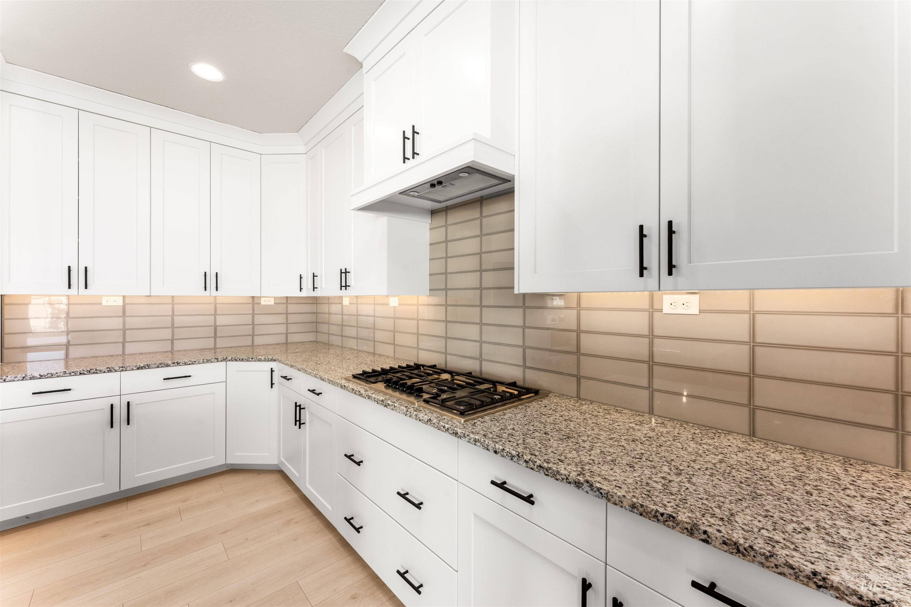 8084 Tandy Cv Street Middleton, ID 83644 - Photo 8 of 46 Kitchen featuring light stone countertops, white cabinetry, light wood-style flooring, decorative backsplash, and recessed lighting