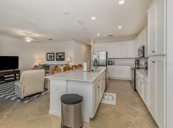 a large white kitchen with cabinets chairs and a refrigerator