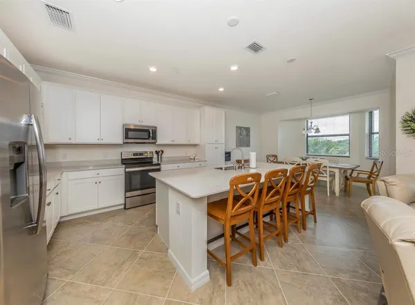 a kitchen with stainless steel appliances kitchen island granite countertop a table chairs sink and cabinets