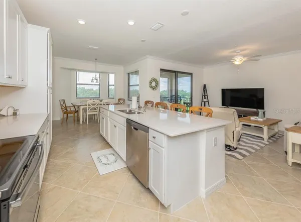 a kitchen with kitchen island a white counter space a sink a stove and cabinets