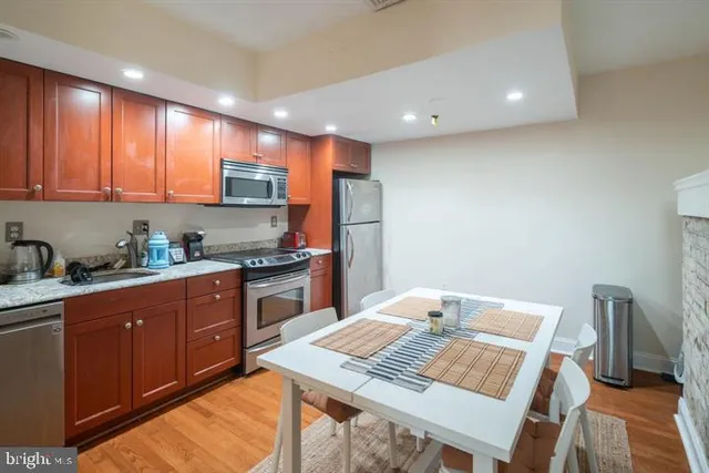 a open kitchen with stainless steel appliances granite countertop a stove a sink dishwasher and a refrigerator with wooden floor