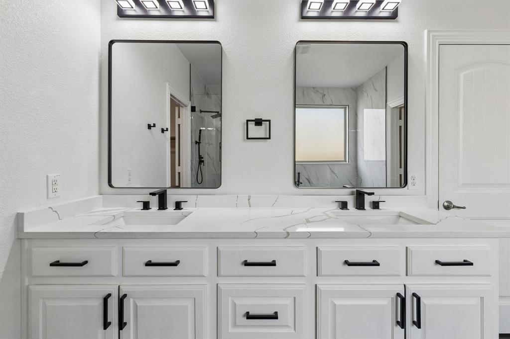 537 Hunt Farms Road Fate, TX 75189 - Photo 22 of 36 Dual vanity with integrated sinks, black fixtures, white cabinetry, and rectangular mirrors