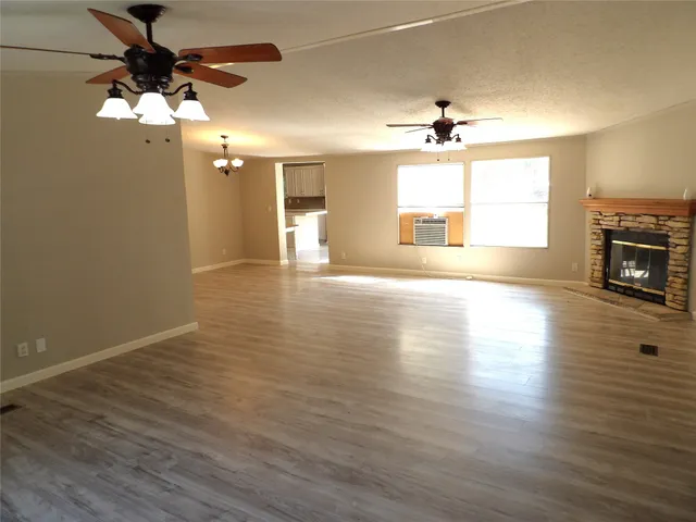 an empty room with wooden floor ceiling fan and windows