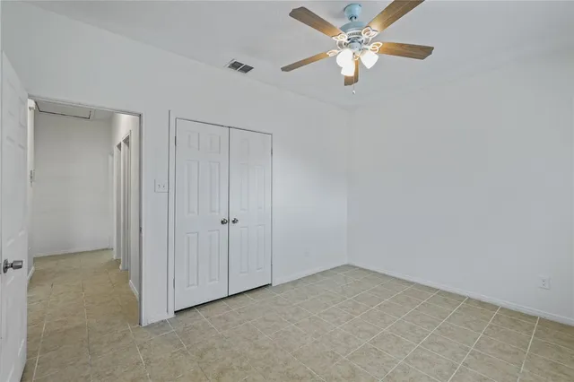 an empty room with closet and a chandelier fan