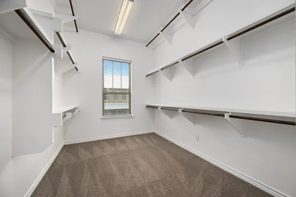 an empty room with chandelier fan and windows