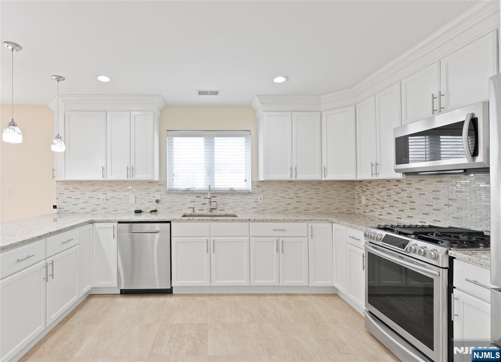 902 Spruce Street Roselle, NJ 07203 - Photo 4 of 32 a kitchen with white cabinets stainless steel appliances and sink