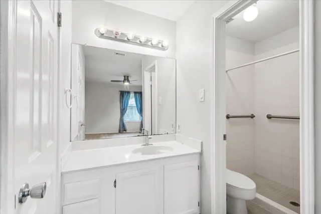 a bathroom with a granite countertop sink a toilet and shower