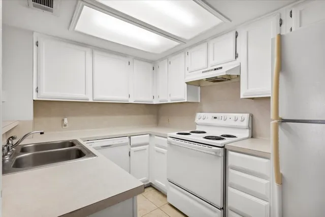 a kitchen with white cabinets and white appliances