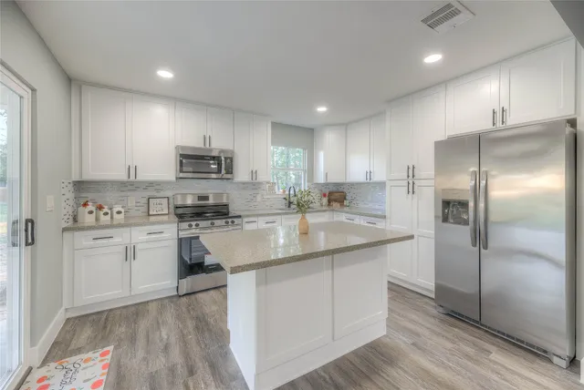 a kitchen with kitchen island a sink stainless steel appliances and cabinets