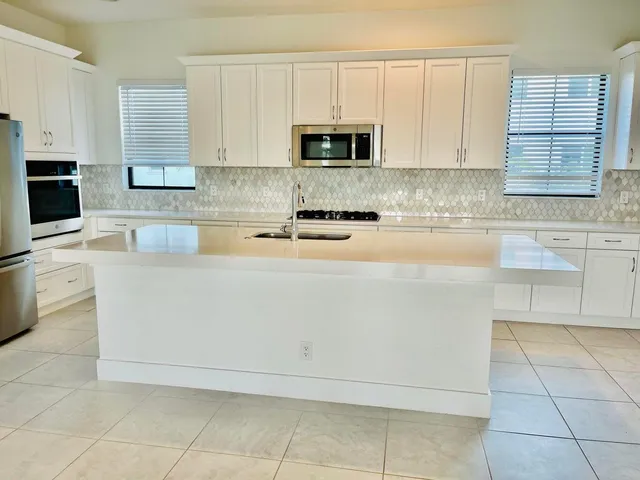 a white kitchen with granite top and white stainless steel appliances