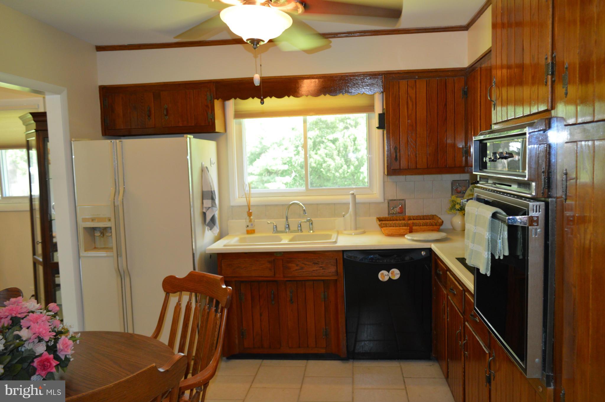 2308 Reckord Road Joppa, MD 21085 - Photo 8 of 17 a kitchen with stainless steel appliances granite countertop a refrigerator a sink dishwasher a stove and a dining table with wooden floor
