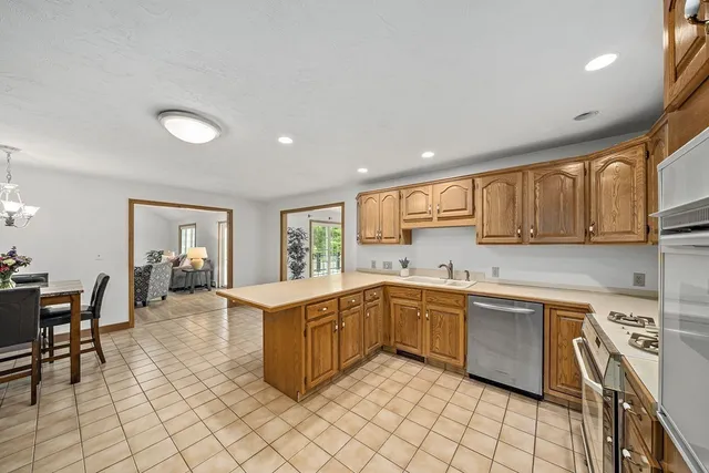a large kitchen with stainless steel appliances lots of white cabinets a sink and a stove