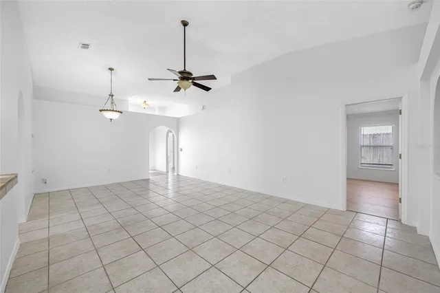 a view of an empty room and chandelier fan