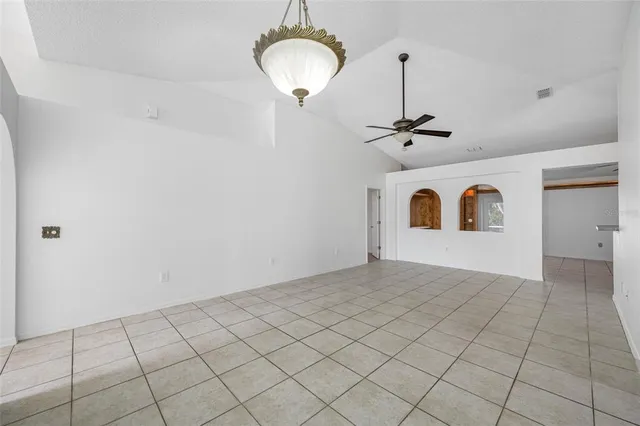 a view of a livingroom with a chandelier fan and kitchen view