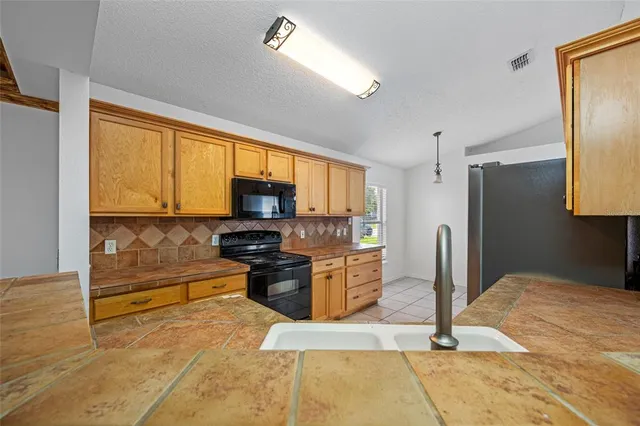a kitchen with stainless steel appliances kitchen island granite countertop a refrigerator stove and sink